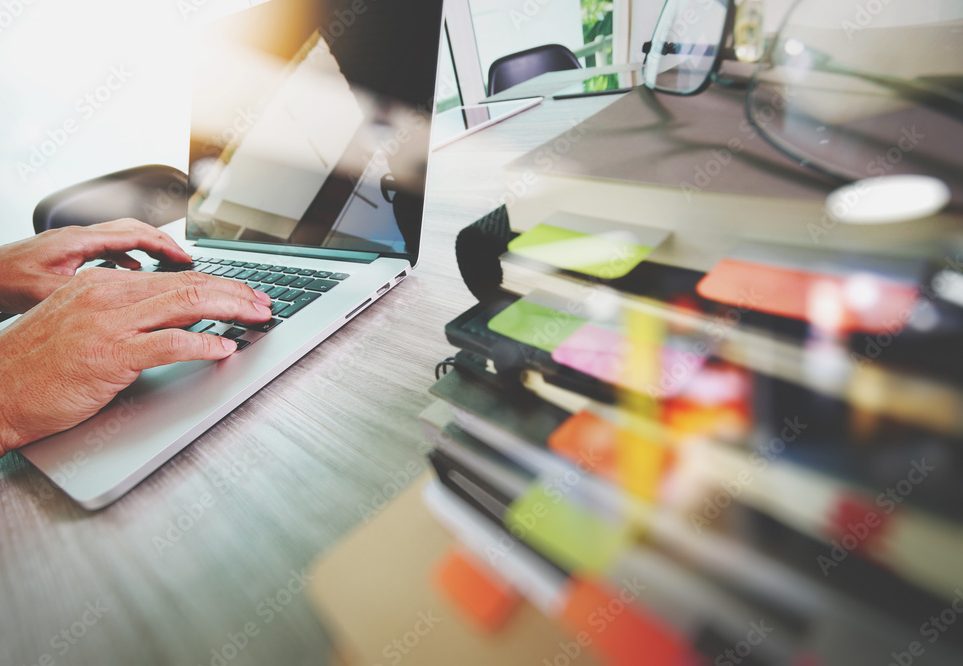 Hands typing on laptop at a desk